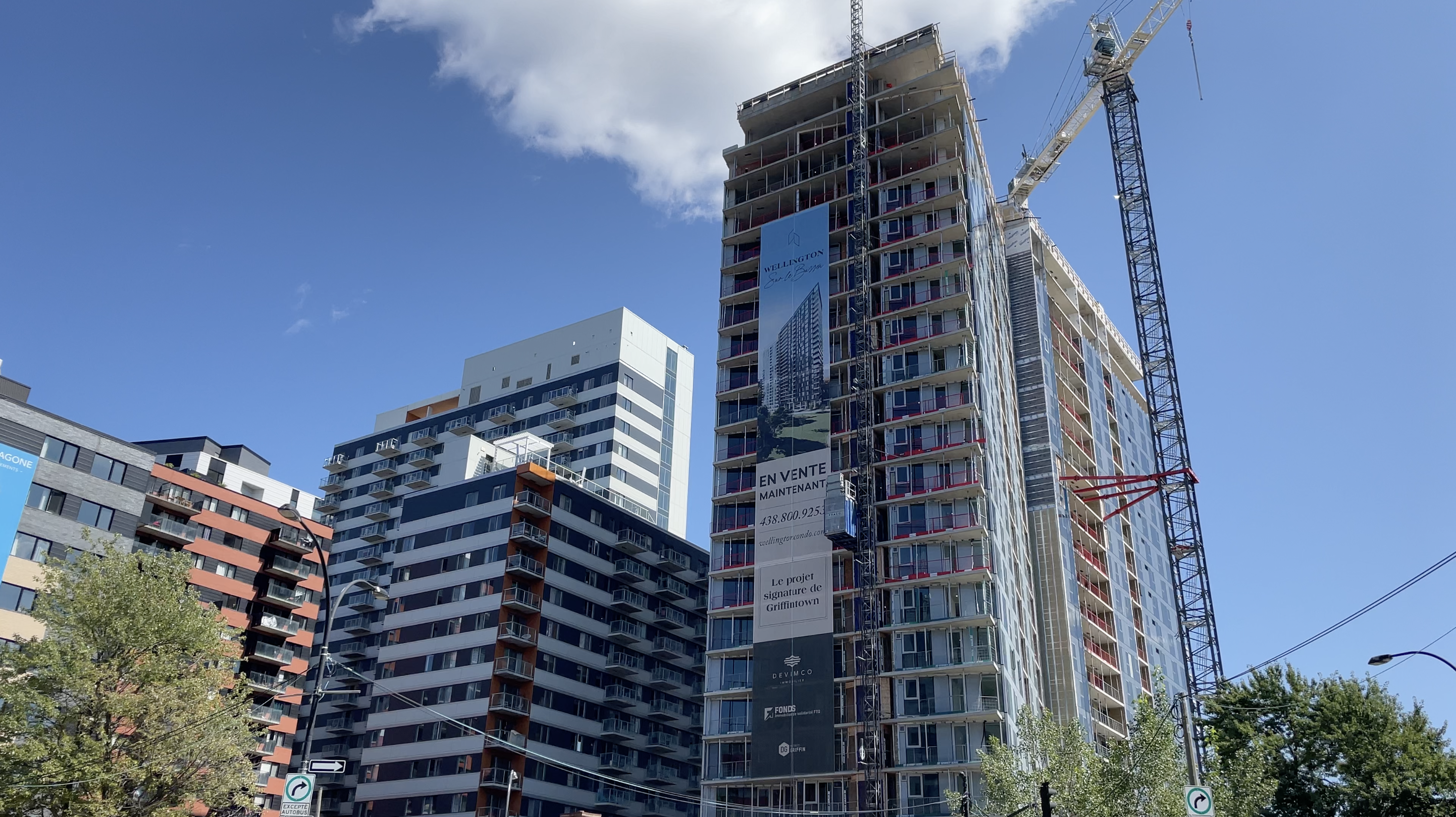 A high-rise condo tower under construction in Montreal's Griffintown neighbourhood, surrounded by mid- and high-rise buildings.